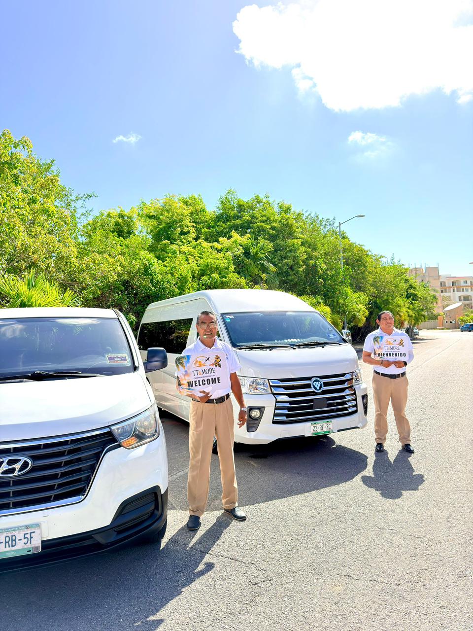 Two TT & More drivers standing with welcome signs beside the fleet